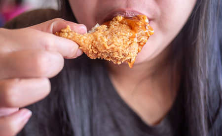 Woman eating fried chicken blurred background, Street food in thailandの写真素材