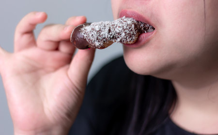 Close up, Woman eating chocolate donut on blurred backgroundの写真素材