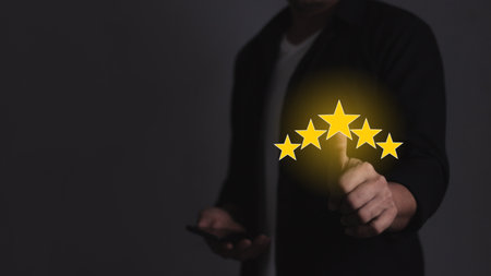 Customer Satisfaction, Young Man with smartphone hand touching five star to review and give 5 stars with very good results in service, Good review 5 star rating choice feedbackの写真素材