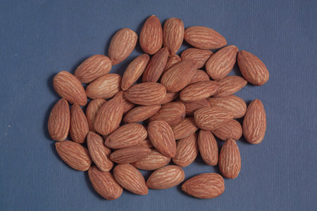 Almonds rest on a simple piece of paper, highlighting their natural texture in a clean minimal...