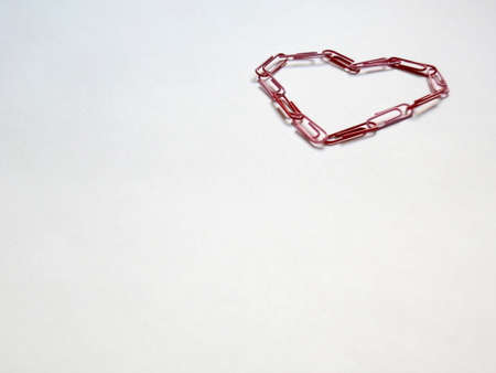 Heart made with red clips on a white paperの写真素材