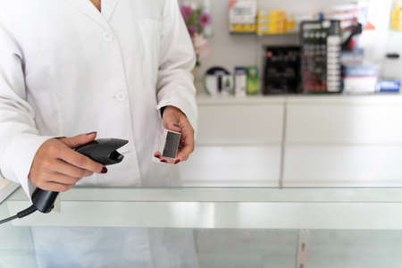 hands of a pharmacist girl checking a medicine with a machine on a tableの写真素材