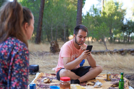 boy in the picnic field looks at the mobile doubting. selective focusの写真素材