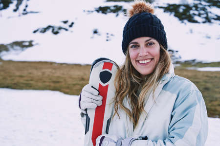 pretty girl poses looking at the camera while laughing while holding the ski equipment. happy carefree girl.の写真素材