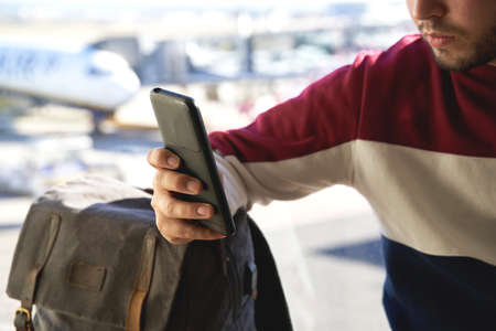 boy's hand resting on his backpack consults the mobile phone. no faceの写真素材