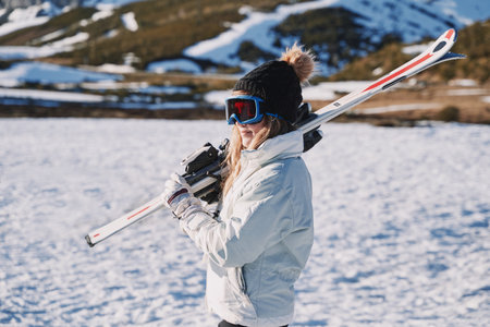pretty girl equipped with a hat and glasses carries some skis in the snow. sun dayの写真素材