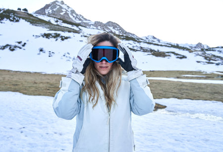 pretty girl puts on her snow goggles to protect herself on the mountainの写真素材