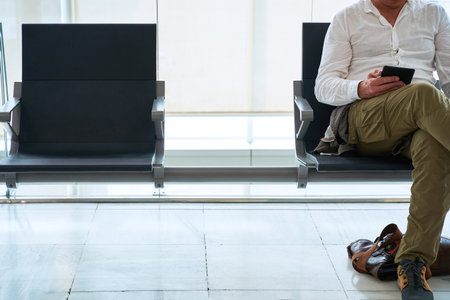 man reads an electronic book while waiting sitting in an airport lounge. no face, copy spaceの写真素材