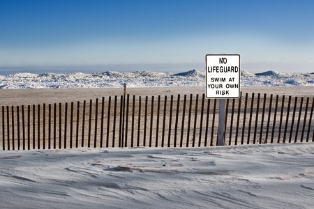 a sign says no lifeguard in front of a snowy beachの写真素材