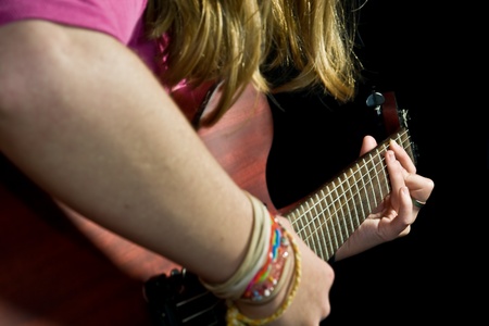 girl playing an electric guitar with black background