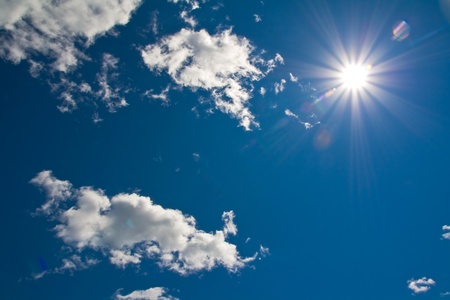 sun shining down from a clouded sky with sunflareの写真素材