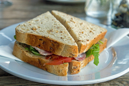 A close up landscape format shot of a wholegrain bacon sandwich on a plate.の写真素材