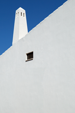 Abstract image of the white wall and chimney of a mediterranean house against a dark blue skyの写真素材