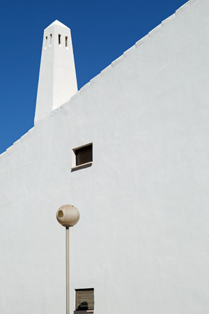 Abstract image of the white wall and chimney of a mediterranean house against a dark blue skyの写真素材
