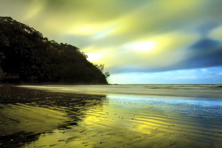 Long exposure seascape over fast moving clouds with wind blowing water and sandの写真素材