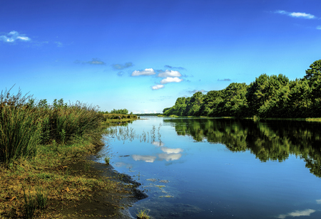 Serene lake with fisherman in background under blue skiesの写真素材