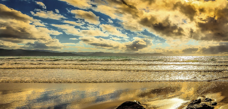 Tranquil isolated beach with lazy waves and puffy cloudsの写真素材