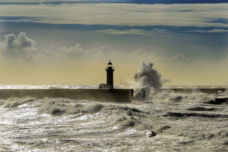Lighthouse deluged by huge wavesの写真素材