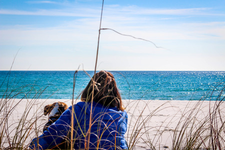 Beautiful beach scene of the Emerald Coast of Florida with people and dog, Waves slowly washing ashore. Sky is deep blue, water a beautiful teal, and the sand is a sugary white all in the Florida panhandle.の写真素材