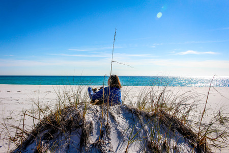 Beautiful beach scene of the Emerald Coast of Florida with people and dog, Waves slowly washing ashore. Sky is deep blue, water a beautiful teal, and the sand is a sugary white all in the Florida panhandle.の写真素材