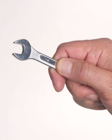 Hand holding a small wrench on white backgroundの写真素材
