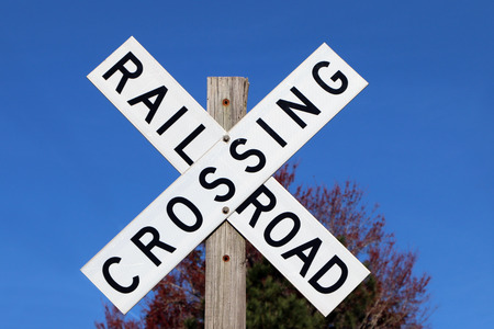 Railroad crossing sign against blue sky background