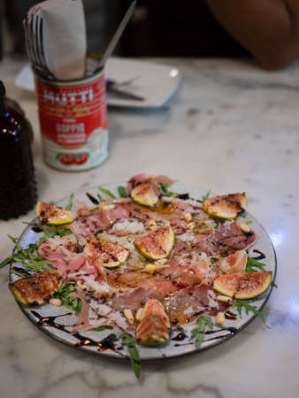 a plate of parma ham salad with pine nut fig and olive oil for appitizer in italian restaurant