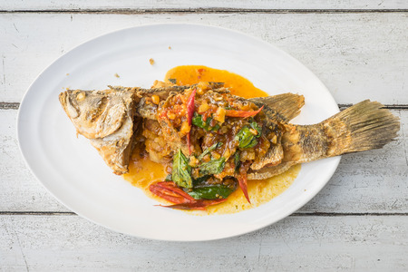 fried fish with fresh herbs and sweet spicy sauce on plate