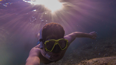 man diving inside the water making snorkling with the sun on the backgroundの写真素材
