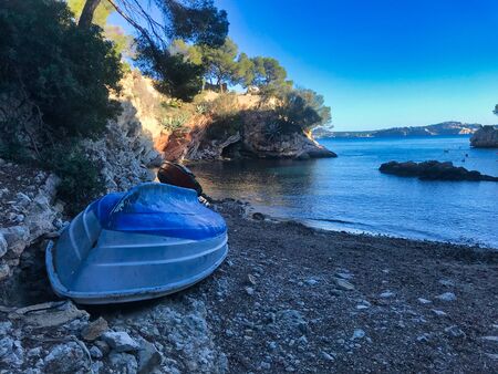 break small boat at a rocky small beach in mallorca, mediterranean sea, spain.の写真素材