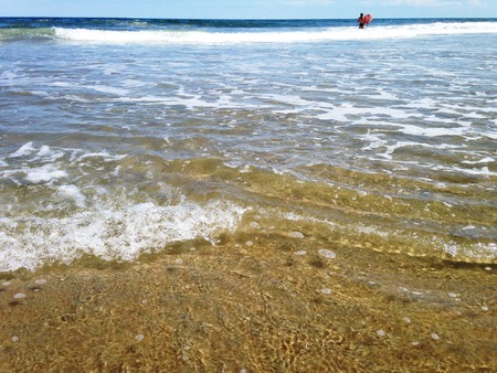 Surfer in water at beach with sand and oceanの写真素材