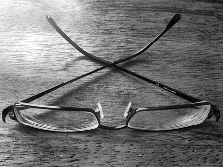 Black and white of eye glasses on a wood tableの写真素材