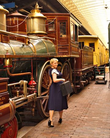 Attractive blonde woman at train station with luggage.