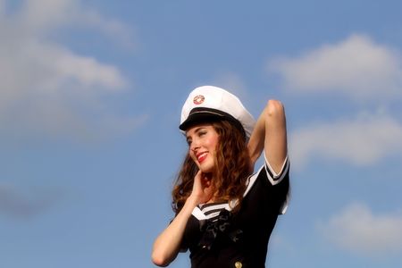 Happy beautiful young woman posing in uniform with blue sky in background.の写真素材