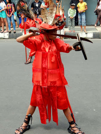 Kabasaran kid, traditional warrior from Minahasa wearing red traditional outfit hold spear or sword....