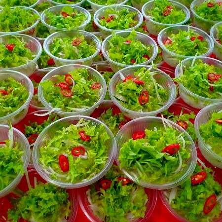 Fresh green salad consist of lettuce, slices of onion and tomatoes are served on plastic bowls