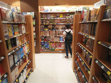 Manado, Indonesia - March 19th, 2016: A girl with a backpack looking for a book on bookshelves in Gramedia bookstore.のeditorial素材
