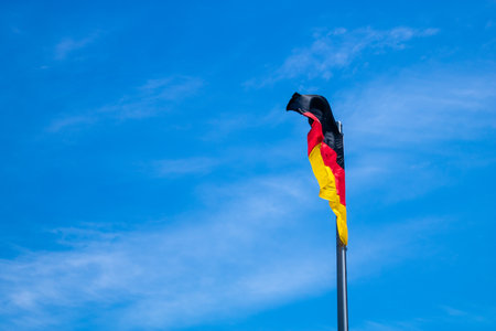Official German flag in the wind and blue sky (front view)の写真素材
