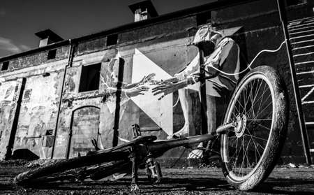 A bike on the ground, old buildings with graffiti in the back - black and white