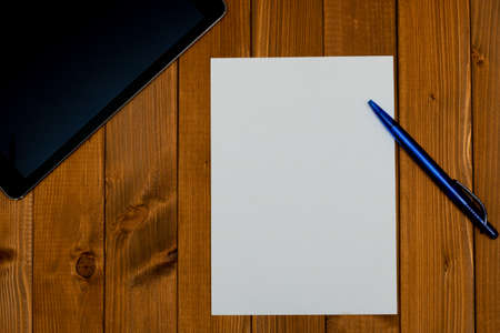 Top view on a workplace with a blank paper, a pen and a tablet