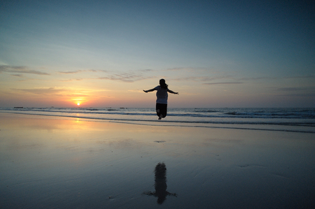 Happy Woman Jumping in Sea Sunsetの写真素材