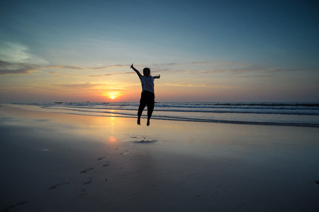 Happy Woman Jumping in Sea Sunsetの写真素材