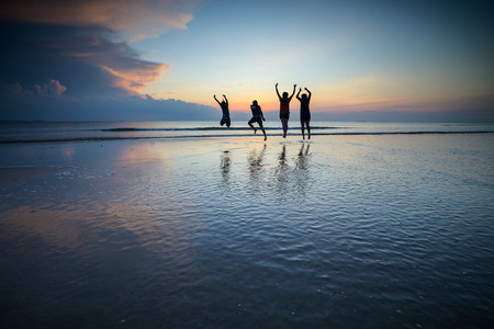Silhouettes of children at sea. Happy children playing at the beach at the dawn time.の写真素材