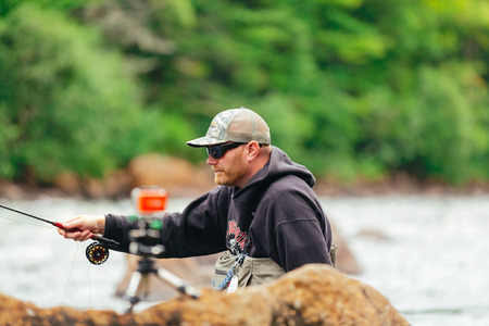 Man Fly fishing on Jacques-Cartier river  in Parc national de la Jacques-Cartier, Quebec.