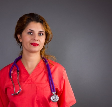 Portrait of  a pretty woman nurse/doctor with stethoscope isolated on grey backgroundの写真素材