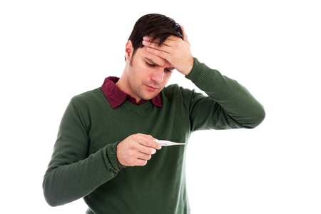 Young man suffering from a cold and checking his temperature on a digital thermometer against whiteの写真素材