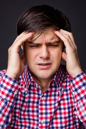 Closeup of  a young  man with headache on gray backgroundの写真素材