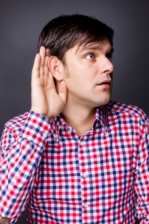 Young man listening with hand on ear isolated over white backgroundの写真素材