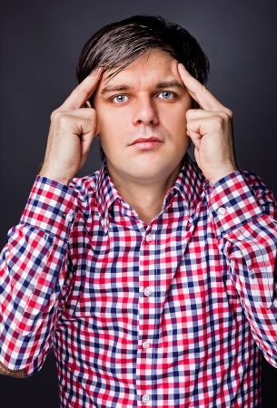 Portrait of young man  thinking hard against gray background の写真素材