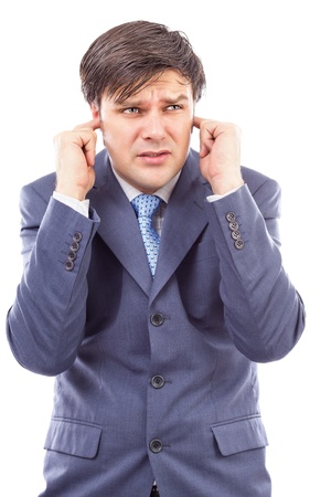 Young businessman with fingers in his ears  protecting himself from noise on whiteの写真素材